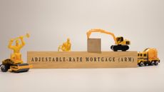 Wooden block that reads 'Adjustable rate mortgage' with toy construction vehicles and workers surrounding it 
