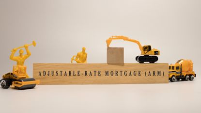 Wooden block that reads 'Adjustable rate mortgage' with toy construction vehicles and workers surrounding it 