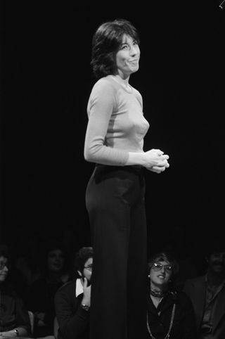 a black and white photo of lily tomlin smiling from the snl stage when she hosted