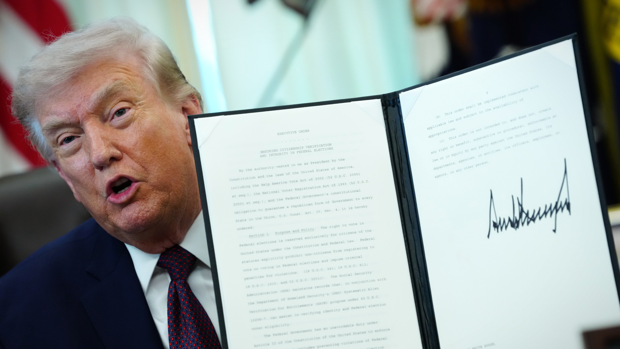 President Donald Trump holds up signed executive order that purports to limit mail-in voting via the U.S. Postal Service