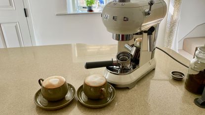 Smeg ECF01 Espresso Machine on counter with two cups of coffee in ceramic cups