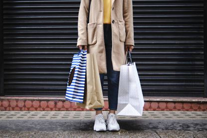 Woman holding shopping bags in front of closed shutter