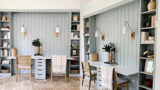pale blue wall of built-in shelves and paneling behind an IKEA desk hack and two chairs