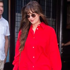 Dakota Johnson wears light wash jeans and a red shirt.