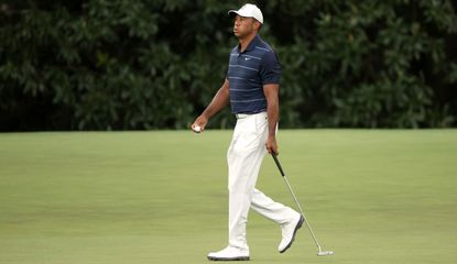 Woods puffs out his cheeks whilst walking with his putter in hand
