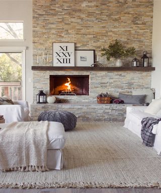 White brick fireplace hearth and surround in rustic contemporary living room with jute rug, white fabric couches and artwork on mantel.