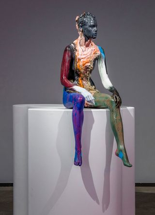 Colorful sculpture of woman sitting on white pillars