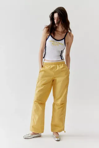 model wears yellow track pant and white tank top and silver ballet flats