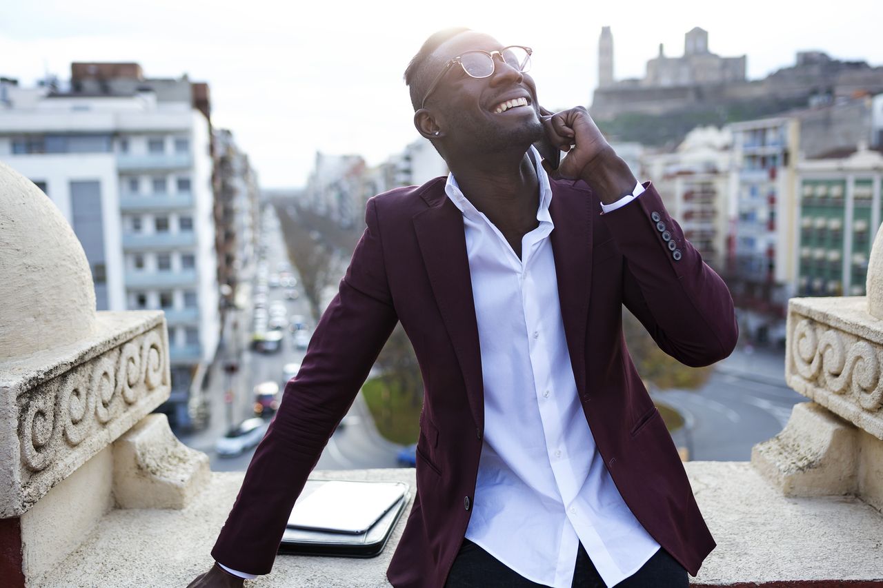 Young entreprenuer takes a business call on the roof deck of his hotel.