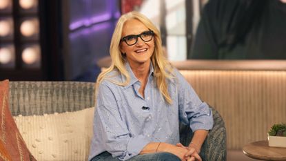 Mel Robbins smiling at the camera in a blue shirt