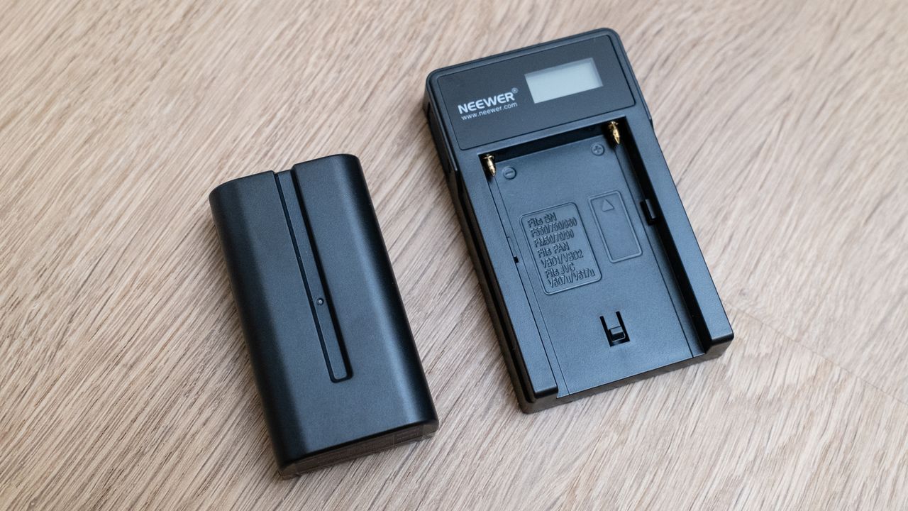 The battery for a Neewer ER1 Motorized Carbon Fiber Camera Slider on a wooden surface