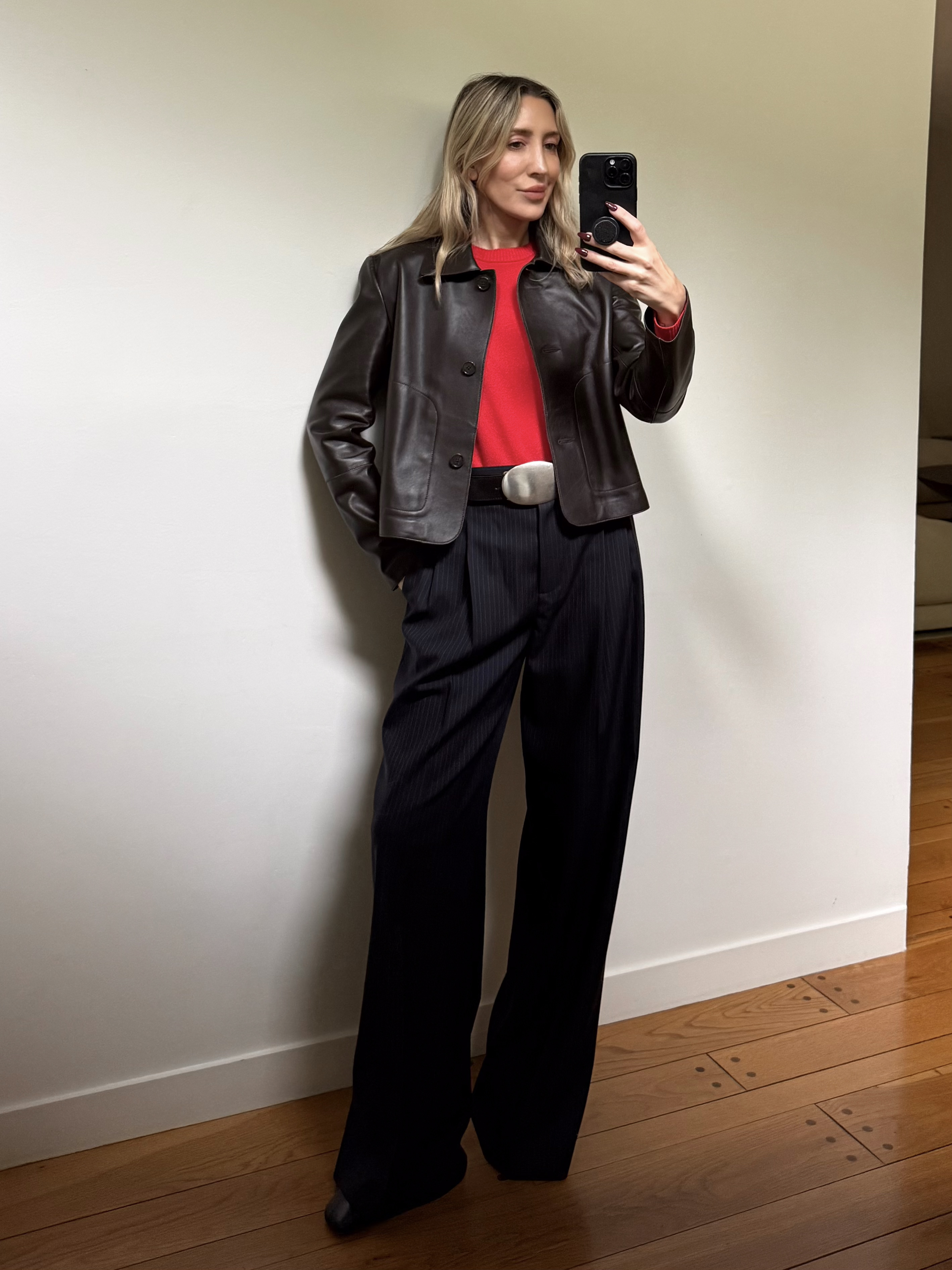 Angela Fink wearing a leather jacket, a red sweater, black pants