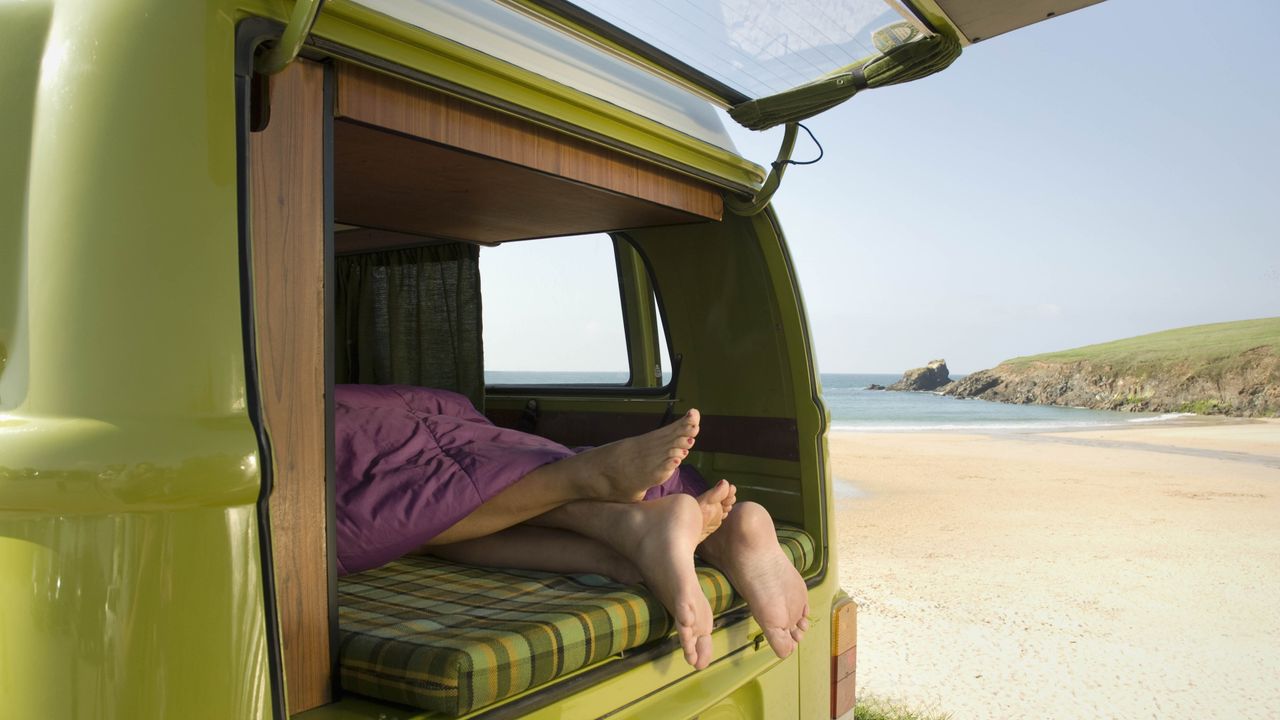 couple&#039;s feet in camper van on beach 