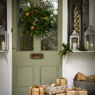Sage green front door with Christmas wreath on top.