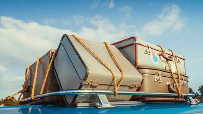 Suitcases tied on top of a car.