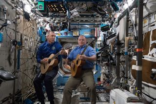 NASA astronauts Drew Feustel (left) and Scott Tingle play guitars together at the International Space Station.