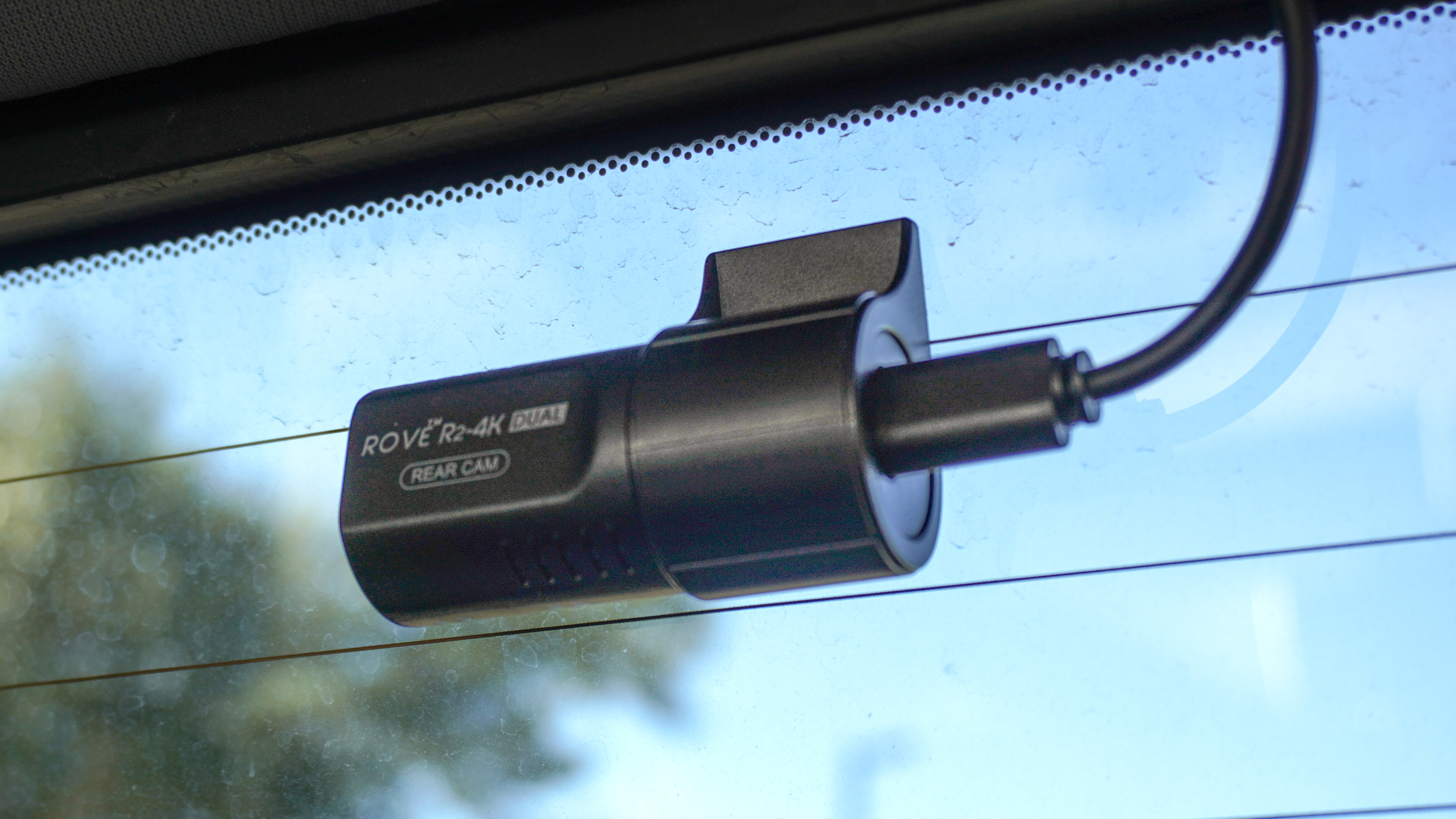 A closeup shot showing the rear camera that comes with the Rove 2K-4K Dual dash cam installed in the back of a truck with its cable cleanly tucked away