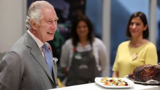 King Charles III reacts while chatting with staff at Morrisons about a joint of roast beef and potatoes at the Supermarkets headquarters during an official visit to Yorkshire on November 8, 2022 in Bradford, England.