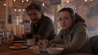 Joel (Pedro Pascal) and Ellie (Bella Ramsey) sitting at a dinner in The Last Of Us episode 6