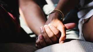 Two people holding hands, sitting on couch in the sunshine, sober dating