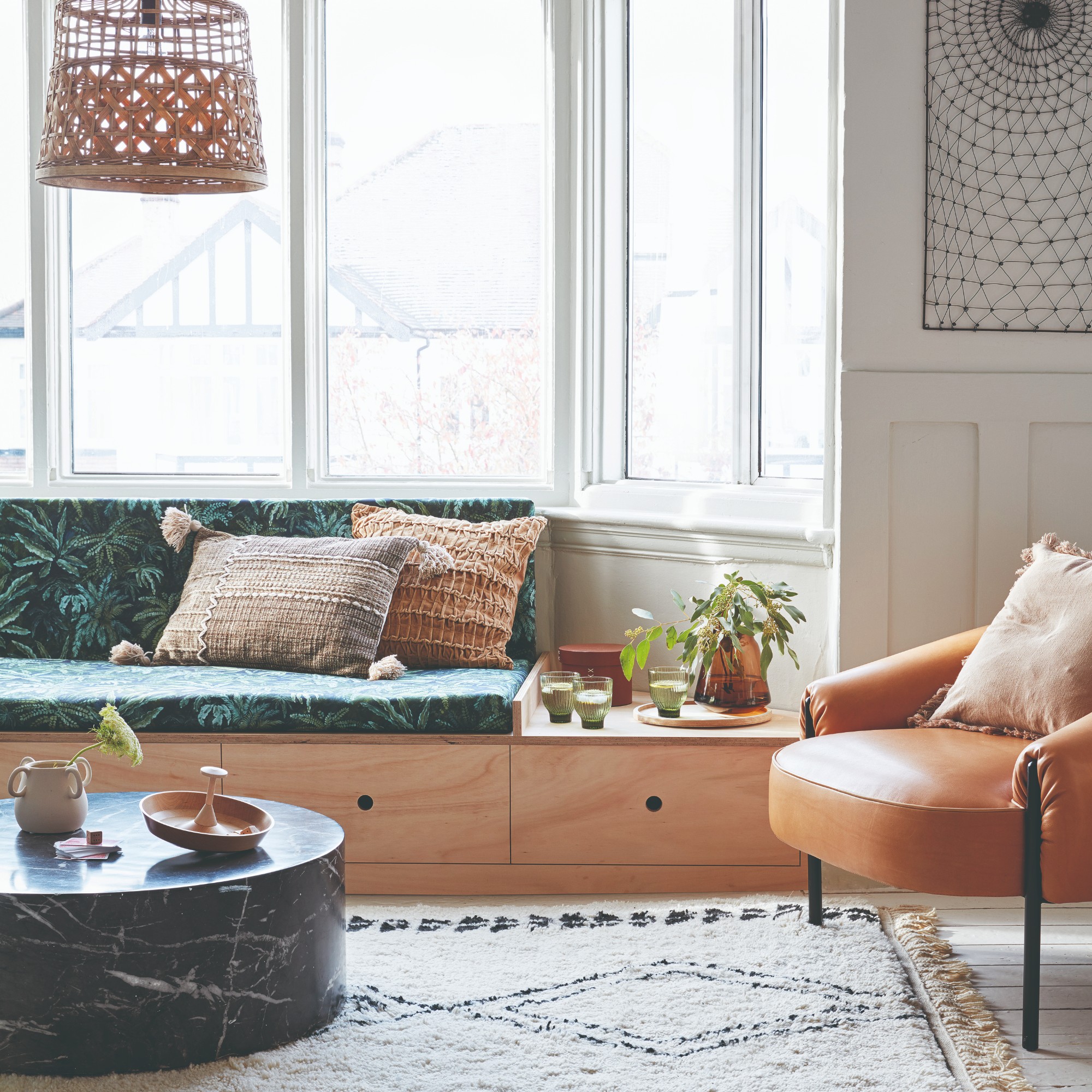 A living room with a bay window with a built-in storage window seat