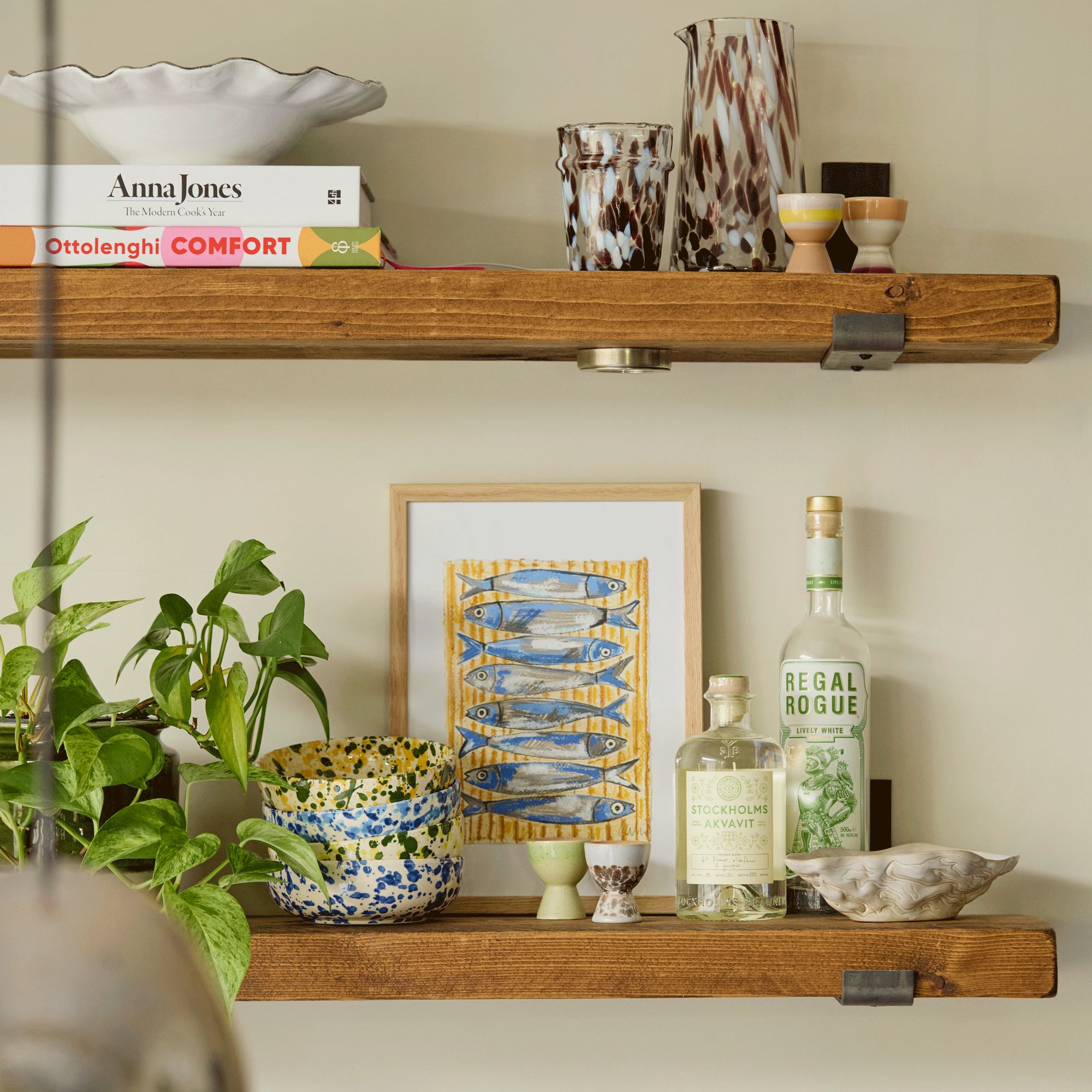 shelves in a kitchen with artwork, plants, accessories and recipe books
