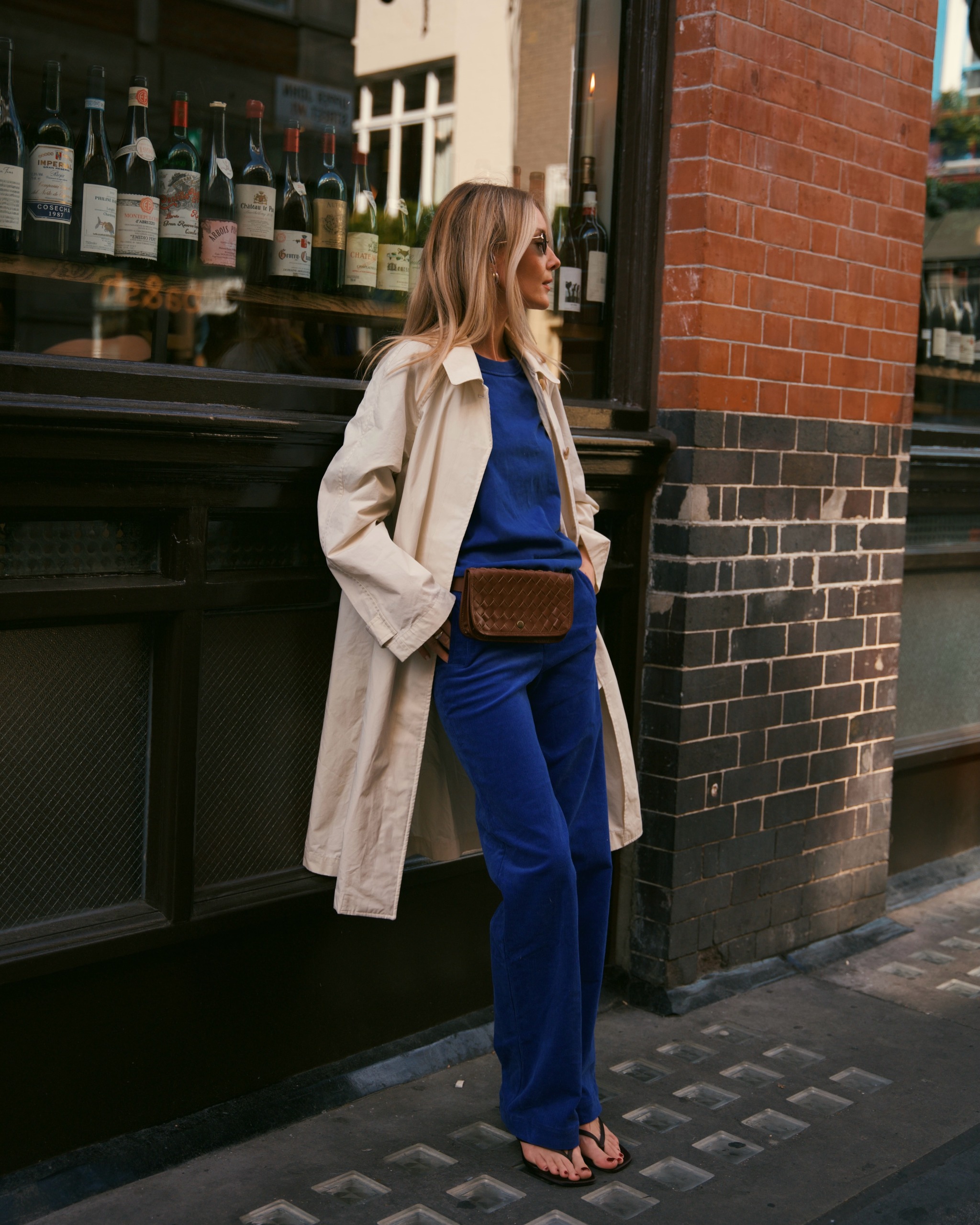 @chloekathbutler wears a cobalt blue jumper and trousers with a beige trench coat
