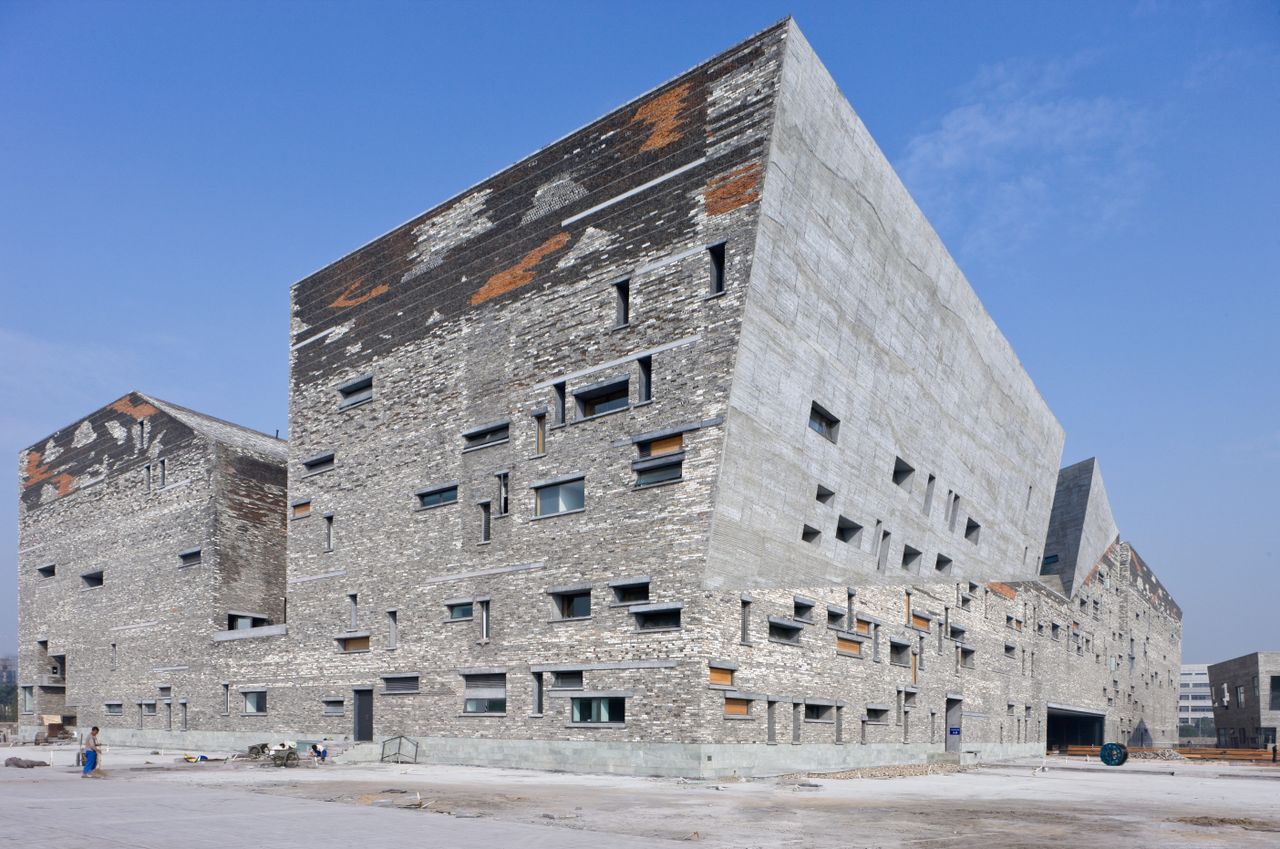 An asymmetrical concrete structure that has many windows of different sizes peppered throughout the structure. 