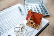 Model of a home resting on paperwork with house keys