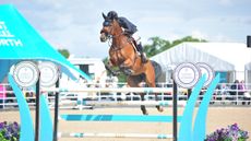 Shane Breen and Be Golden jumping a turquoise blue and white jump at Bolesworth 2024