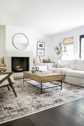 A modern neutral living room with a fireplace, coffee table, and a large area rug