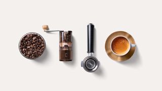 a pot of coffee beans, coffee grinder, portafilter, and coffee mug from a bird's eye view