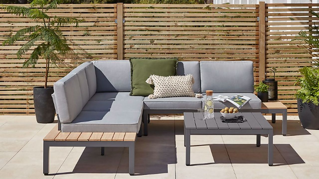 Grey corner sofa in garden with slatted fence