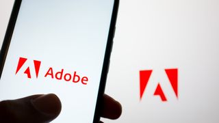 Adobe logo pictured on a smartphone with logo and branding pictured in background.