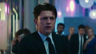 Tom Holland looks confused in the middle of a party in Uncharted.