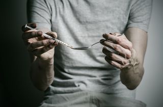 A man fills a syringe from a spoon