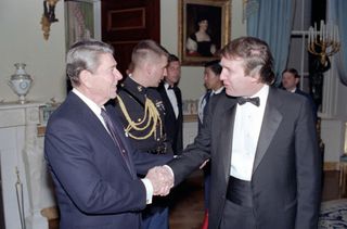 US President Ronald Reagan (1911 - 2004) shakes hands with real estate developer Donald Trump in a reception line in the White House's Blue Room, Washington DC. November 3, 1987. The reception was held for members of the