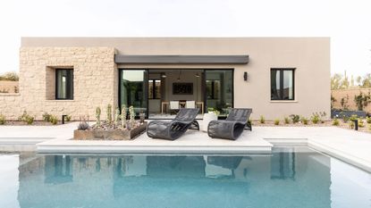 Home with large modern pool with two shapely deck chairs