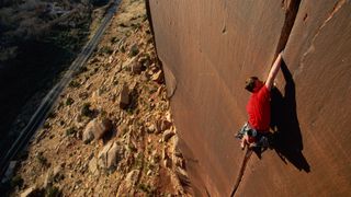 A man in a red shirt crack climbing in Utah