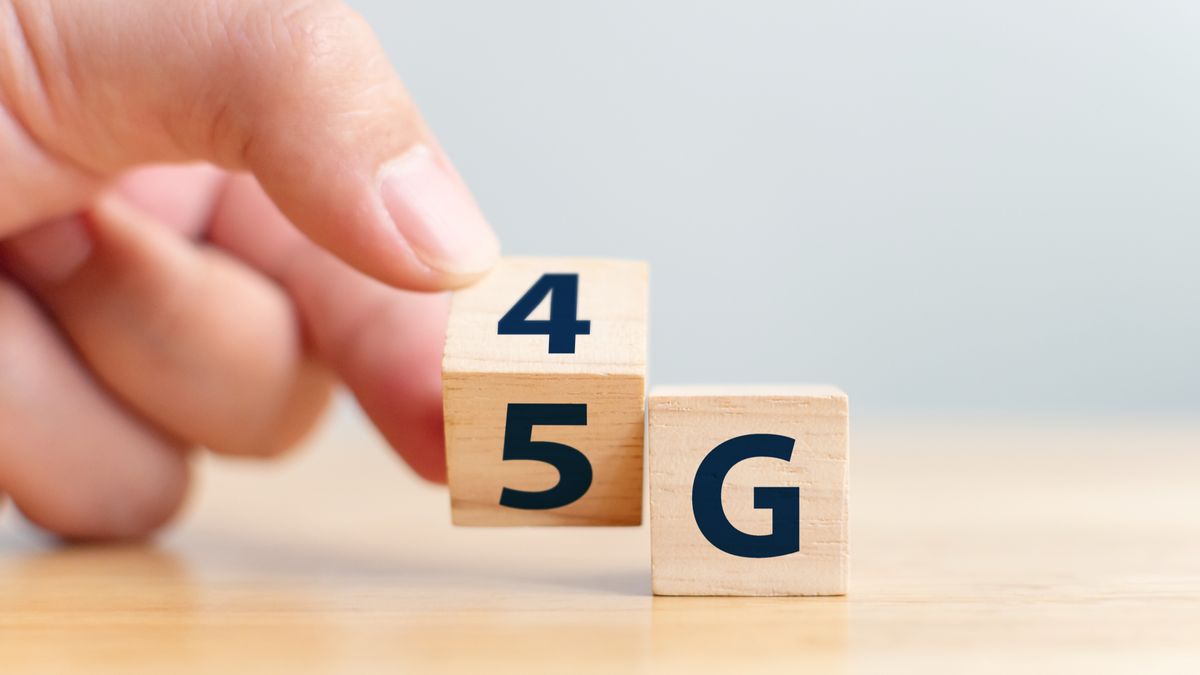 A hand flipping a wooden cube with 4G and 5G printed on it