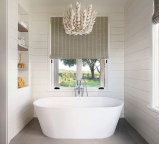 White bathroom with freestanding bath tub and built in shelving