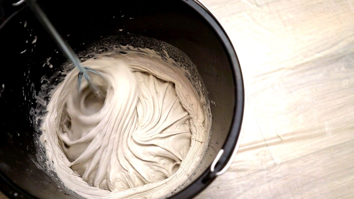 Grout being mixed in a black bucket on a floor with a protective sheer