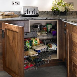 kitchen cabinets with wooden door groceries and flower on marble counter