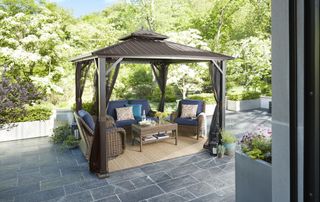 Steel gazebo on a large patio with garden furniture underneath