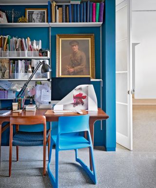 Blue home office with wall of shelving
