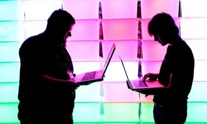 Participants hold their laptops in front of an illuminated wall at the annual Chaos Computer Club (CCC) computer hackers' congress on December 28, 2012 in Hamburg, Germany.