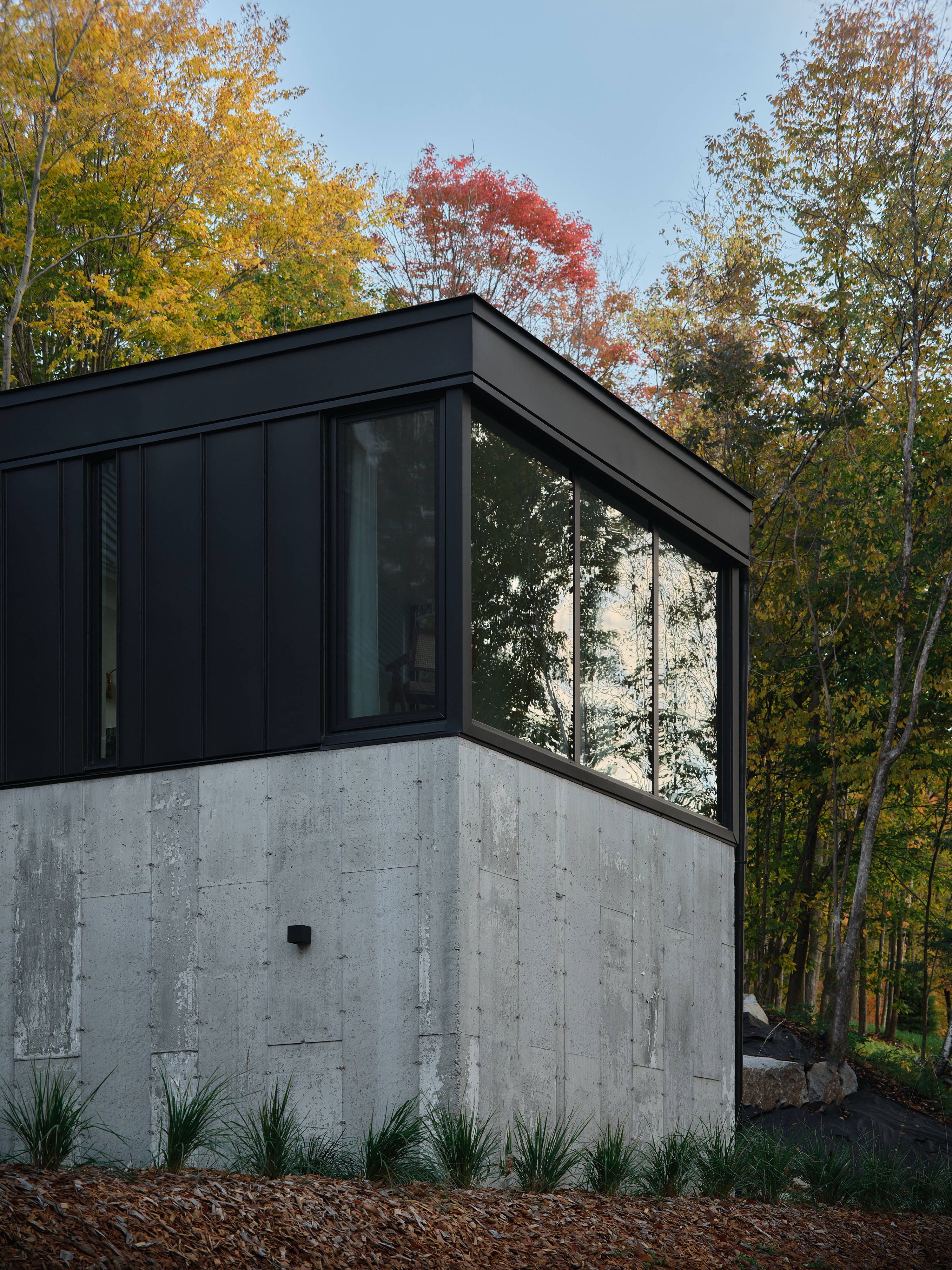 Viewed from outside, the primary bedroom sits atop of the concrete plinth