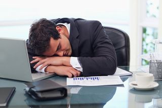 A man sleeps at his desk in an office.