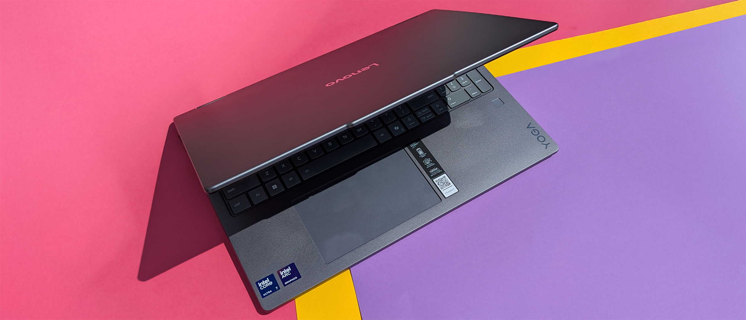 Lenovo Yoga 7i 16 (Gen 10) laptop ajar on pink, yellow, and purple card.