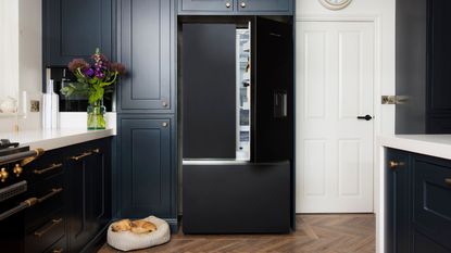 A dark freestanding fridge in a built in kitchen storage unit